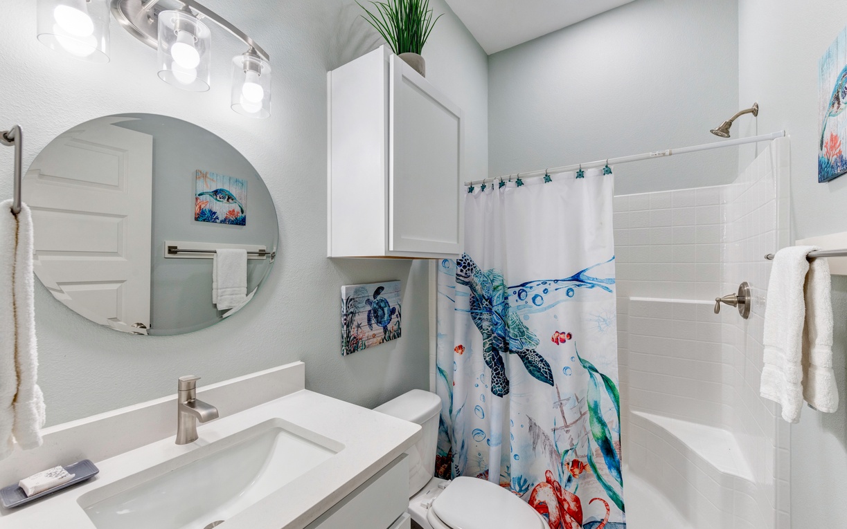 Refresh in your charming sea-themed bathroom featuring ocean artwork, modern fixtures, and a playful turtle shower curtain that brings underwater magic to your stay.