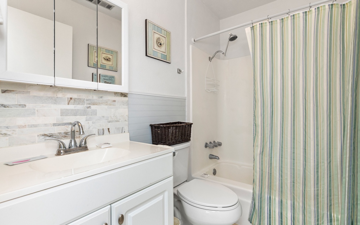 Fresh coastal vibes await in your private bathroom with stylish tile work and cheerful striped accents.