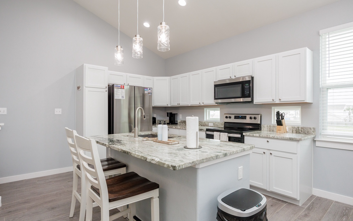 Cook your favorite meals in this bright, fully equipped kitchen with granite countertops, stainless steel appliances, and elegant pendant lighting.