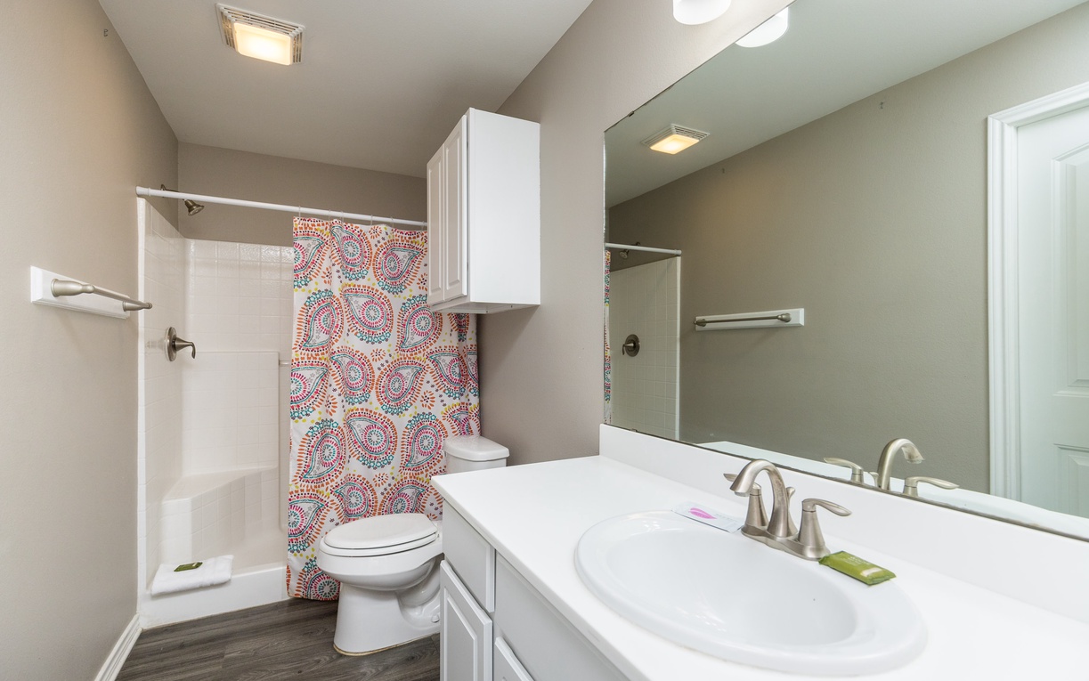 Your private bathroom features modern amenities with a colorful mosaic accent wall, clean white cabinetry, and thoughtful storage.
