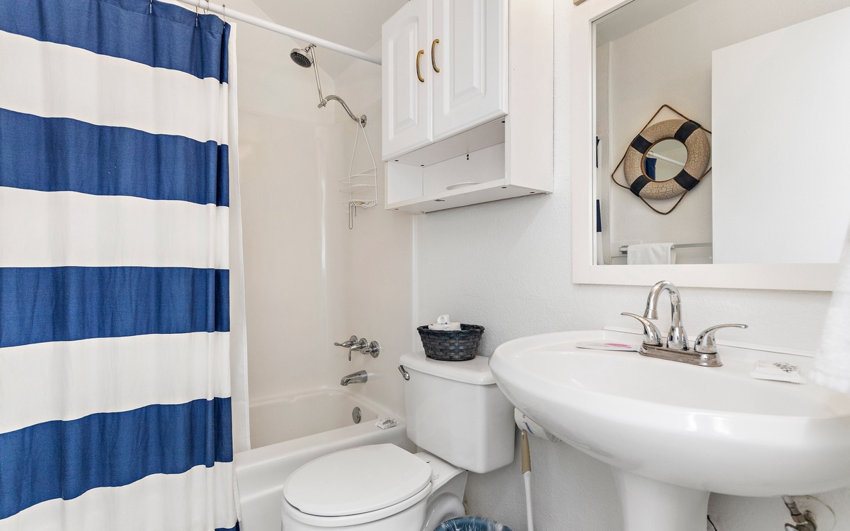 Refresh in your private nautical-themed bathroom with crisp blue striped curtains and coastal charm.