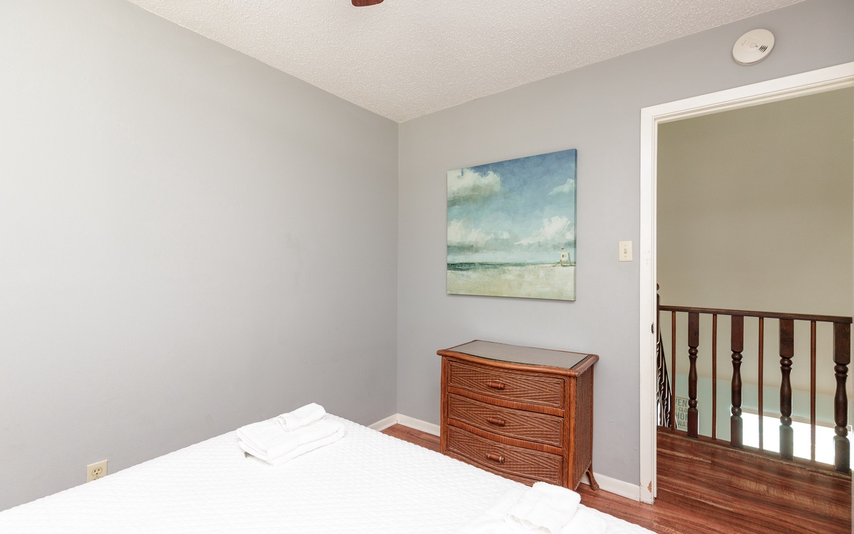 Rest peacefully in your serene bedroom with coastal artwork and warm wood accents creating a tranquil retreat.
