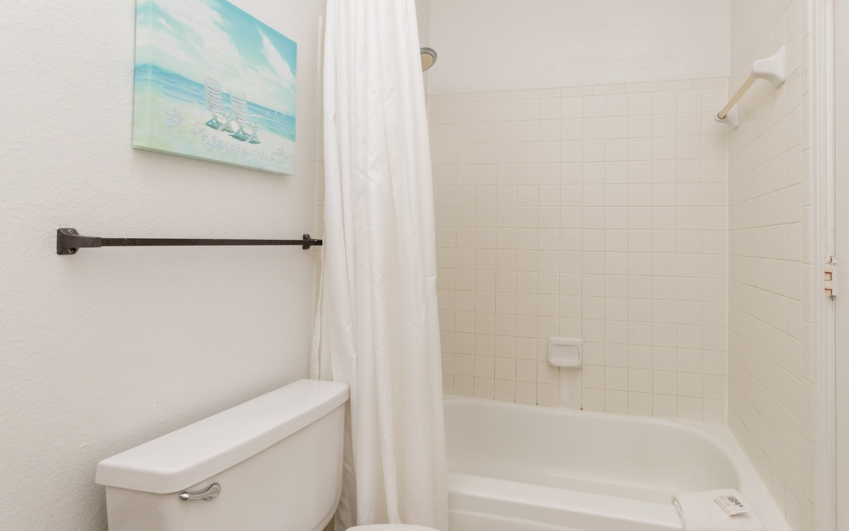 Your private bathroom features a relaxing tub-shower combo with coastal artwork creating a soothing, beachside atmosphere.