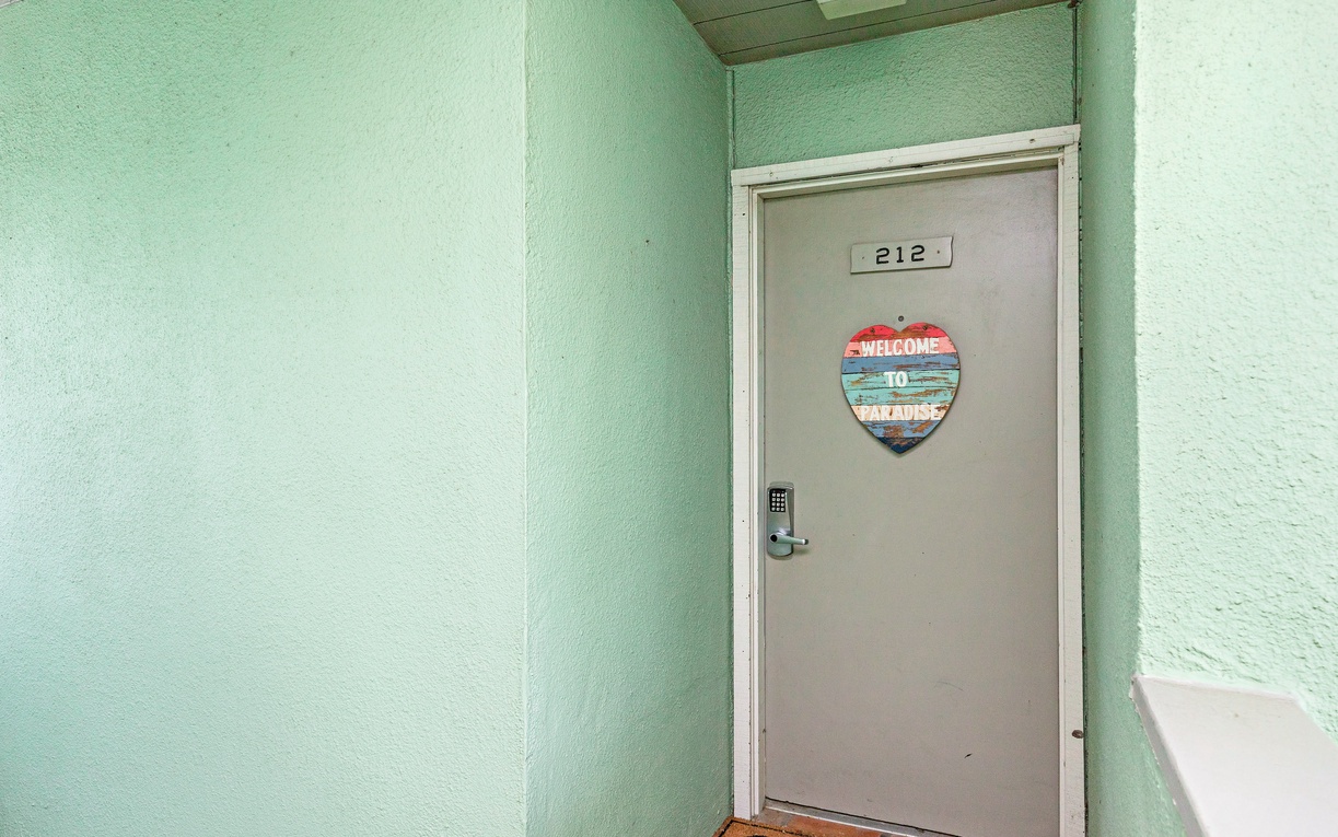 Arrive at your tropical retreat, room 212, where mint-green walls and a cheerful welcome sign set the tone for your getaway.