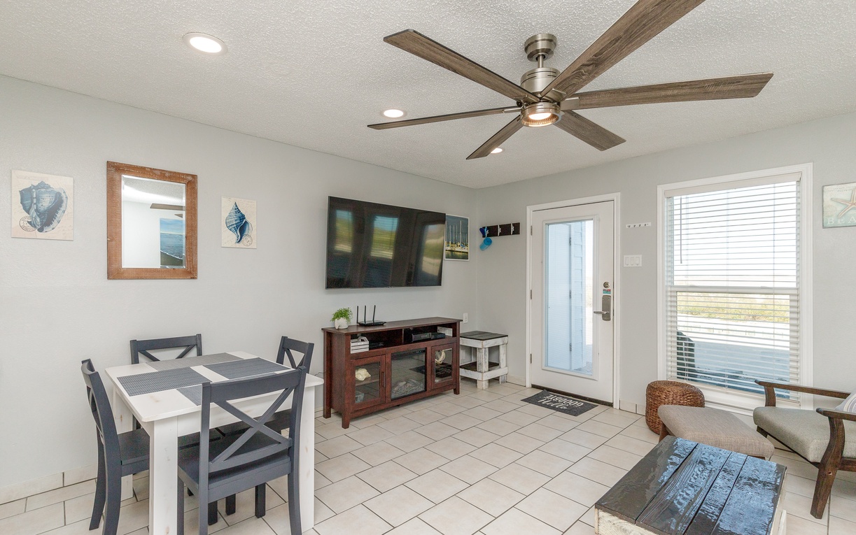 Relax in your bright, airy living space with coastal decor, modern TV setup, and dining for four—perfect for unwinding after beach days.