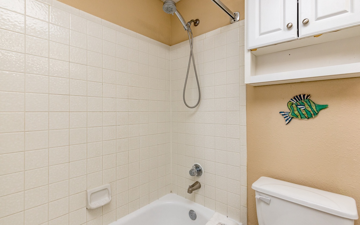 Step into your private bathroom featuring a tub-shower combo with cheerful fish art to brighten your morning routine.