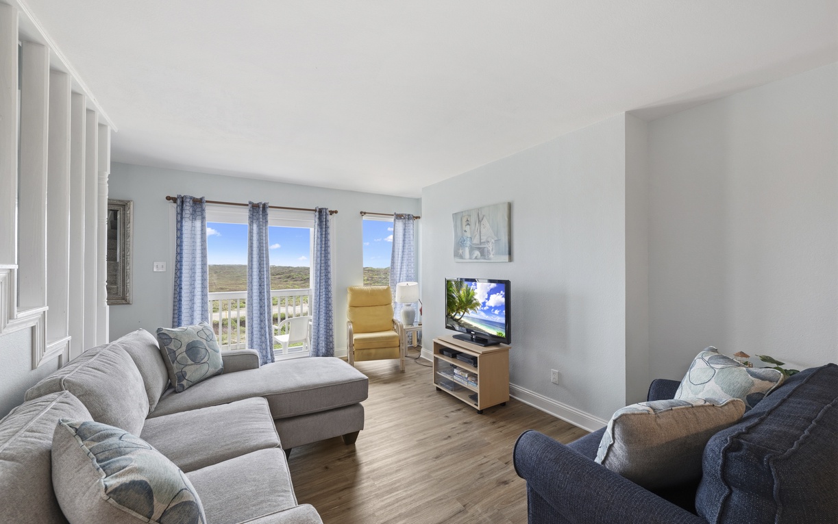 Unwind in your spacious living room with plush seating, natural light, and scenic hillside views creating a bright, peaceful atmosphere to call home.