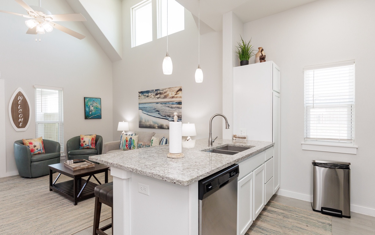 Relax in your bright open-plan space where vaulted ceilings and coastal artwork create an airy, beach-inspired retreat for cooking and unwinding.