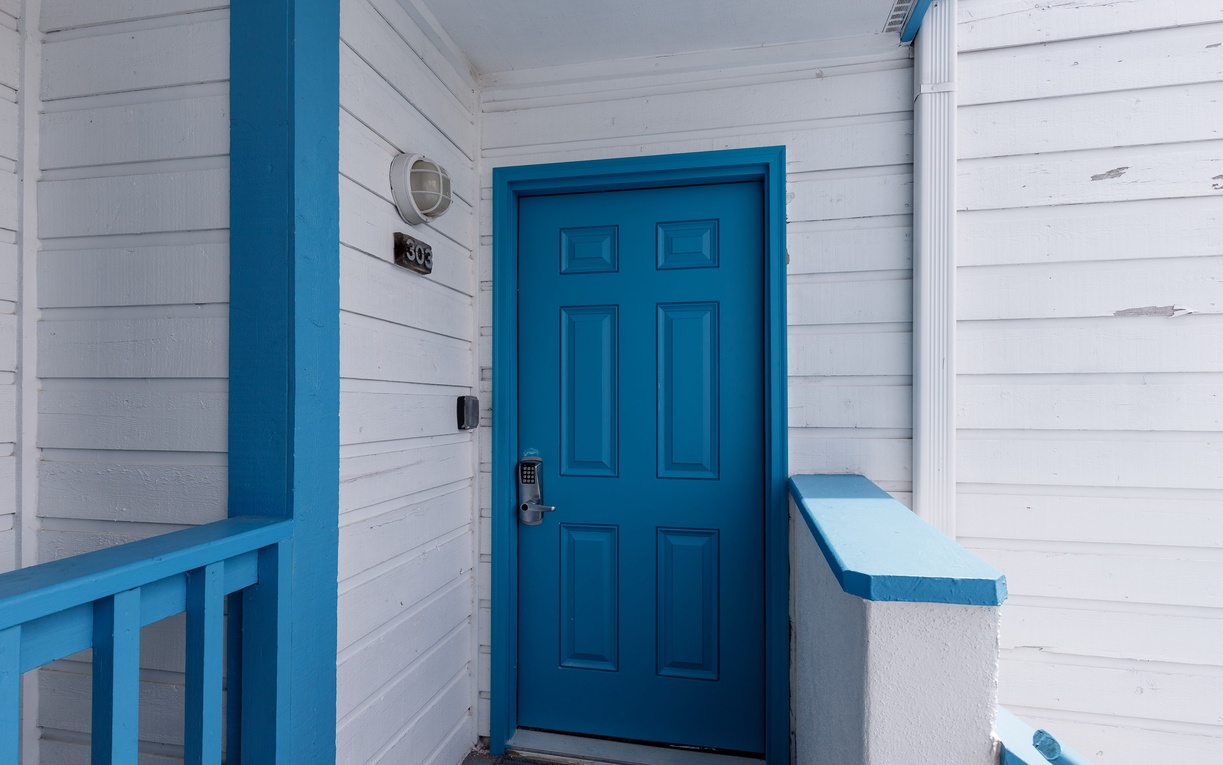 Charming entrance with bright blue door and coastal-inspired white siding welcomes guests to unit 509.