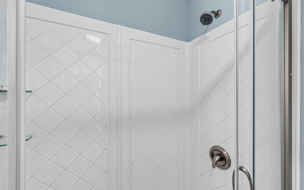 Step into a pristine, spa-like shower with elegant white tile and soothing blue accents—your perfect retreat after a day of adventure.
