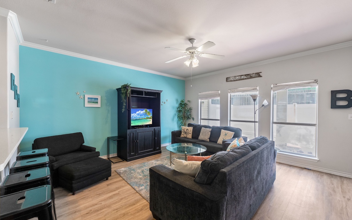 Relax in your spacious living room with comfy sectional seating, vibrant turquoise accent wall, and entertainment center perfect for movie nights.