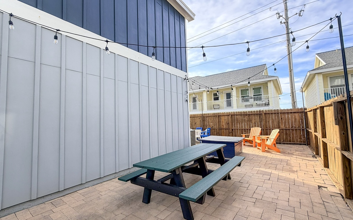 Enjoy your private patio with picnic seating, string lights overhead, and colorful Adirondack chairs perfect for evening relaxation.