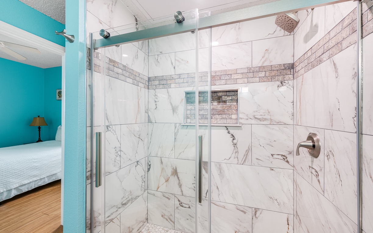 Step into your luxurious marble shower with elegant glass enclosure and rainfall showerhead for the perfect morning refresh.