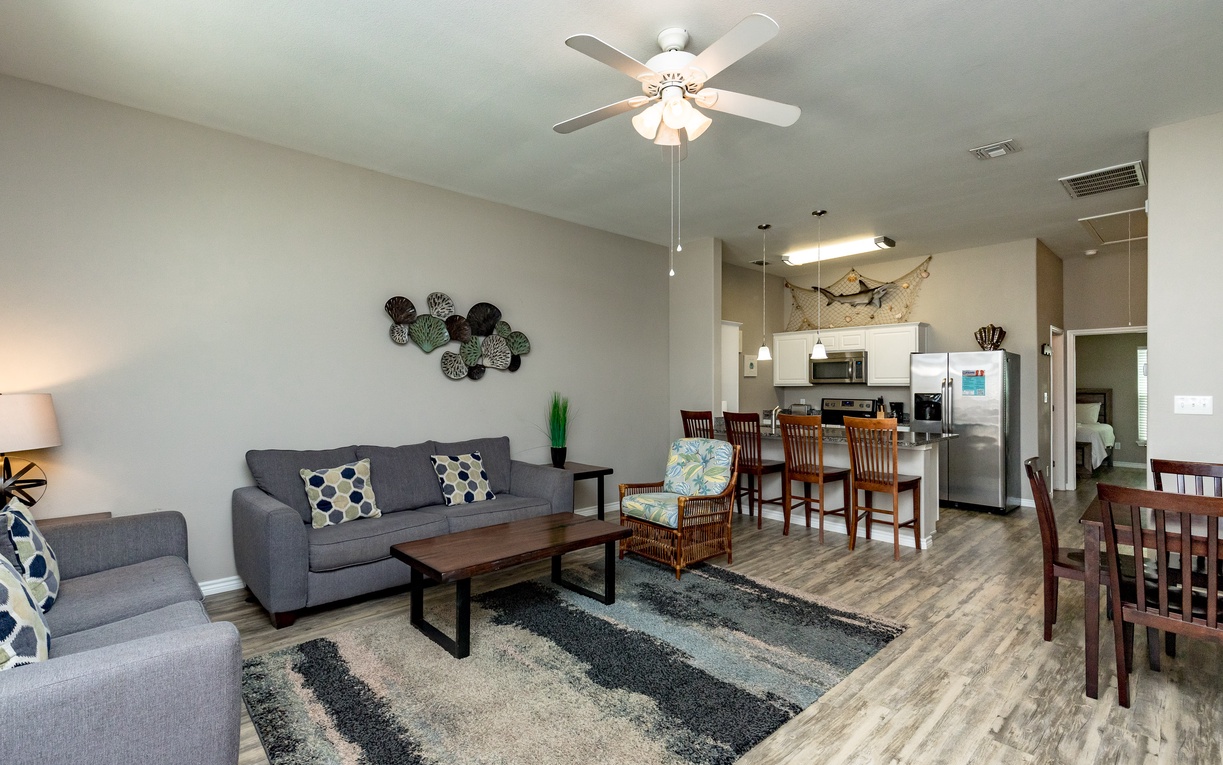 Relax in your spacious open-concept living area where modern comfort meets coastal charm, complete with cozy seating and a fully equipped kitchen.