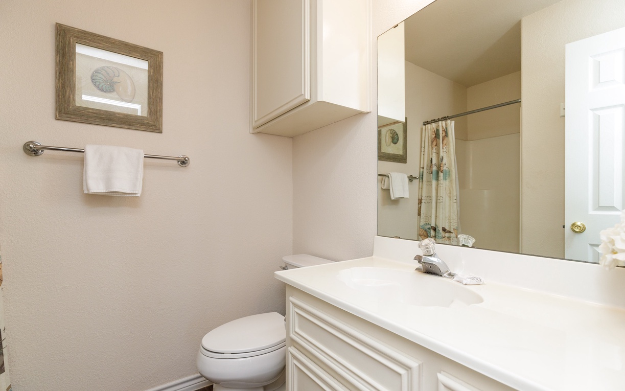 Your bright bathroom features crisp white cabinetry, polished countertops, and thoughtful touches like fresh towels to start your day feeling refreshed.