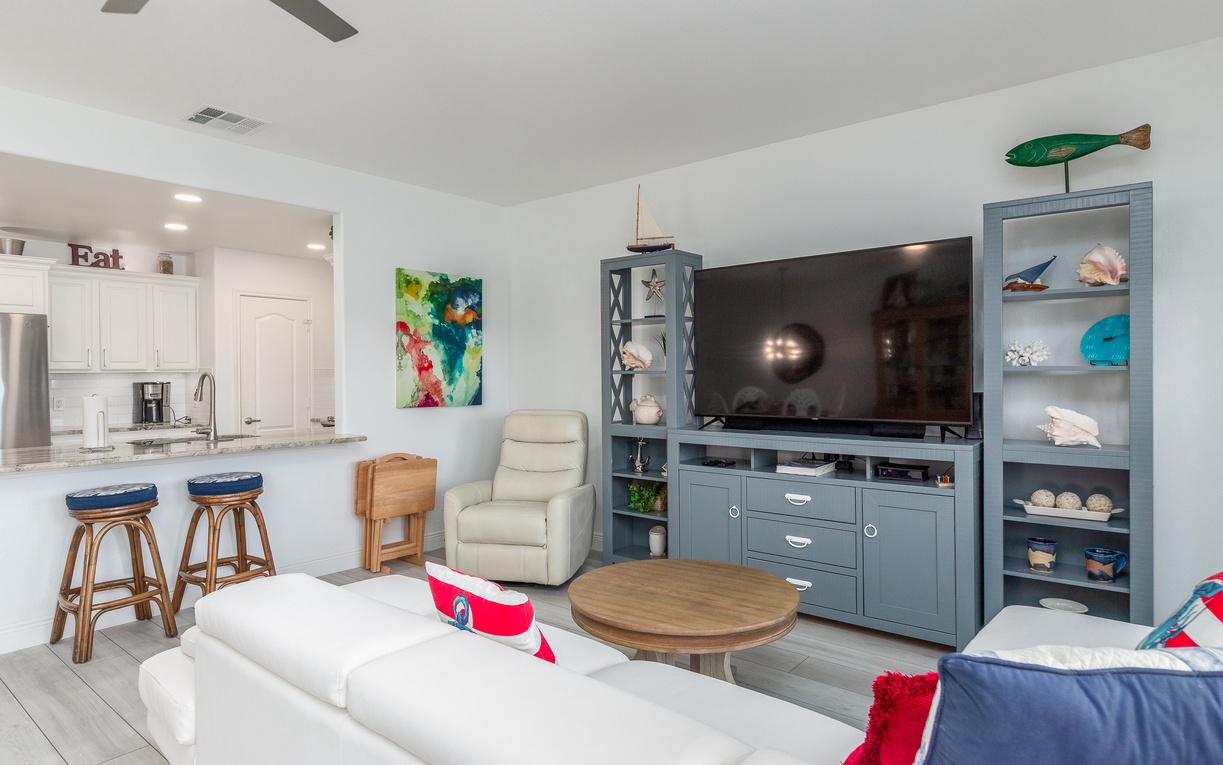 Relax in your bright, coastal-themed living space with modern entertainment center and open kitchen for memorable vacation moments.