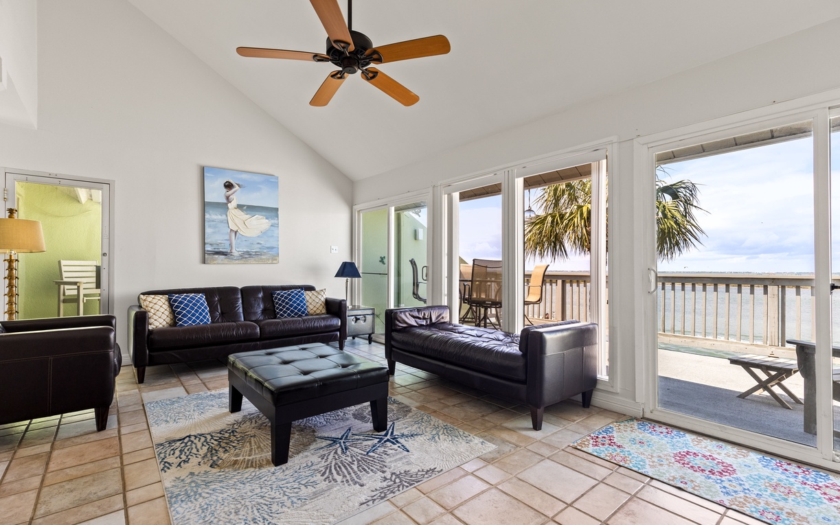 Relax in your spacious living room with plush leather seating and coastal artwork, where sliding doors reveal your private balcony.