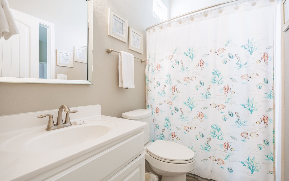 Freshen up in your bright bathroom featuring cheerful ocean-themed decor and all the essentials for your comfort.
