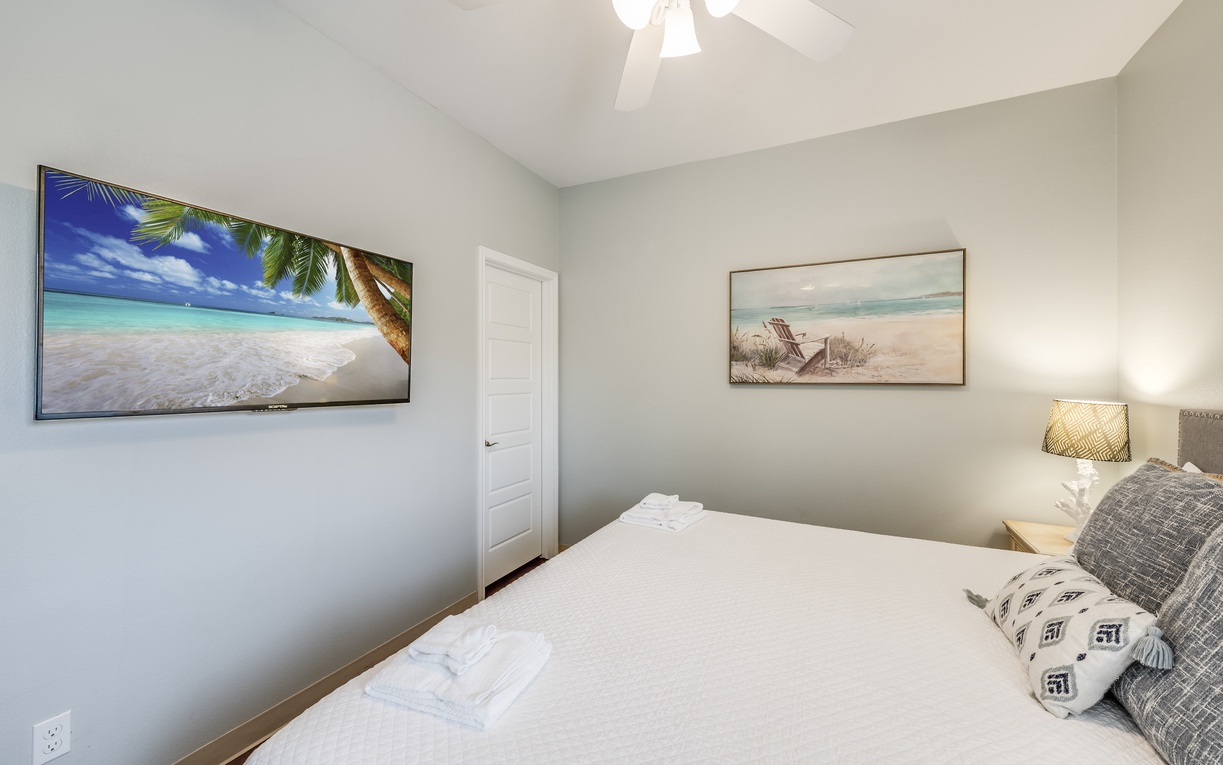 Drift off to sleep in your cozy bedroom, where tropical beach artwork and soft linens create a peaceful coastal retreat.