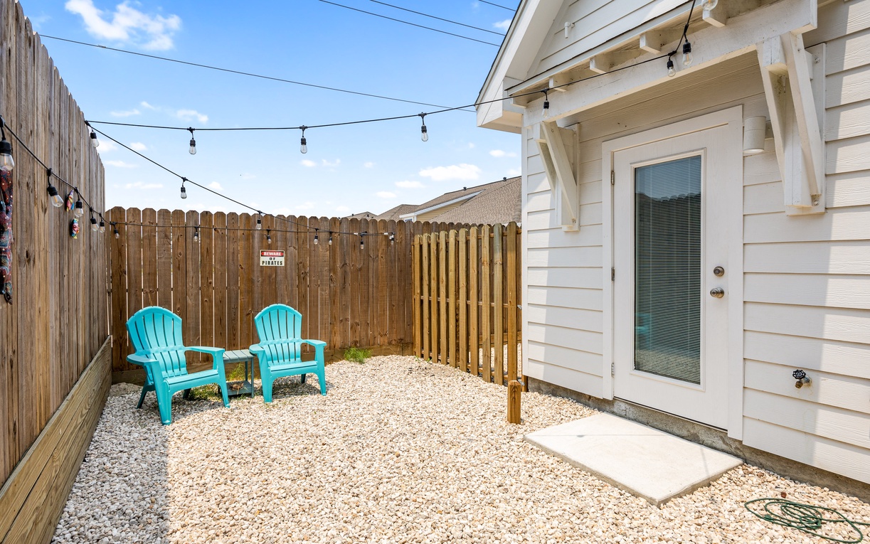 Your private patio offers a peaceful retreat with turquoise chairs under twinkling string lights, perfect for morning coffee or evening relaxation.
