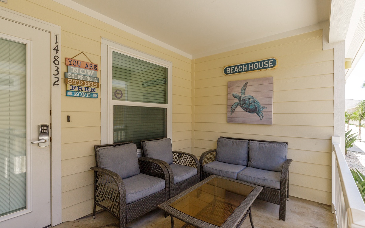 Your covered patio welcomes you with comfortable seating and charming coastal decor, perfect for morning coffee or evening relaxation.