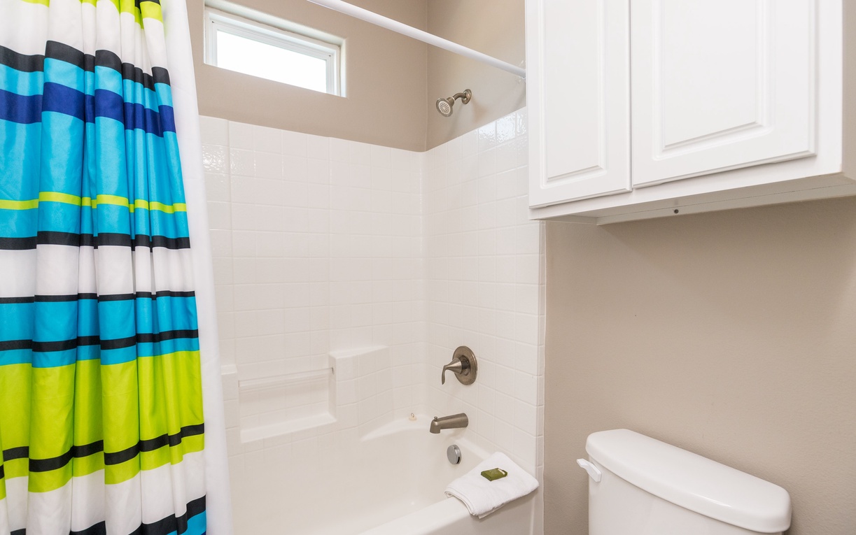 Step into your bright, modern bathroom with a refreshing tub-shower combo and vibrant striped curtain that adds a cheerful pop of color.