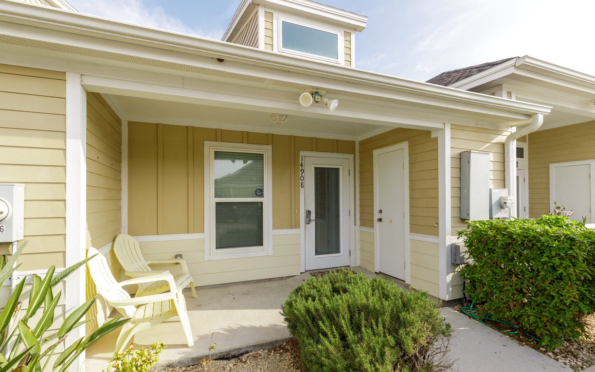 Charming coastal cottage entrance with covered porch and thoughtfully landscaped approach welcomes guests to their peaceful retreat.