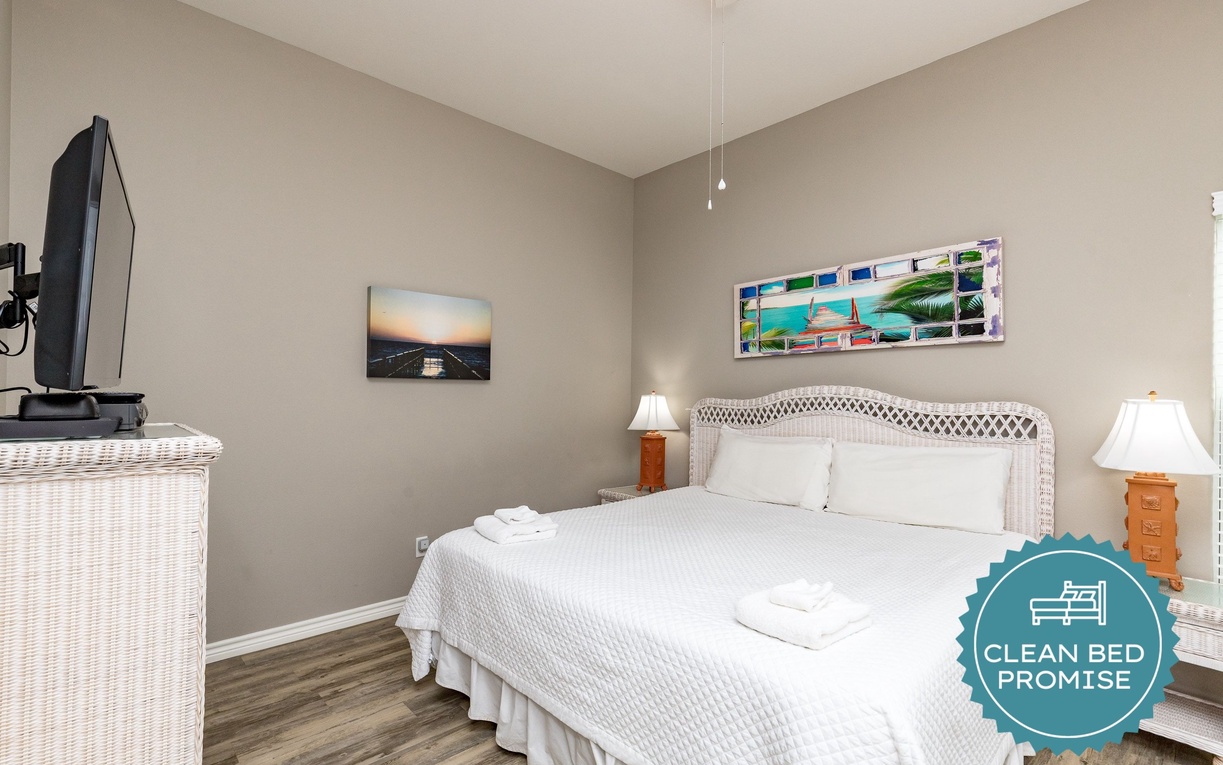 Unwind in your peaceful bedroom with crisp linens, warm lighting, and coastal artwork creating the perfect retreat.