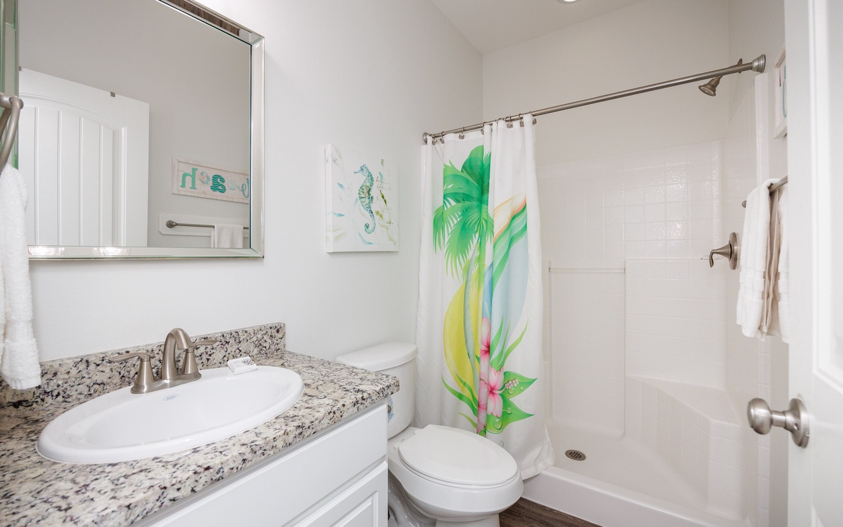Step into your bright, tropical-inspired bathroom featuring granite counters and a cheerful palm shower curtain that brings island vibes to your daily routine.