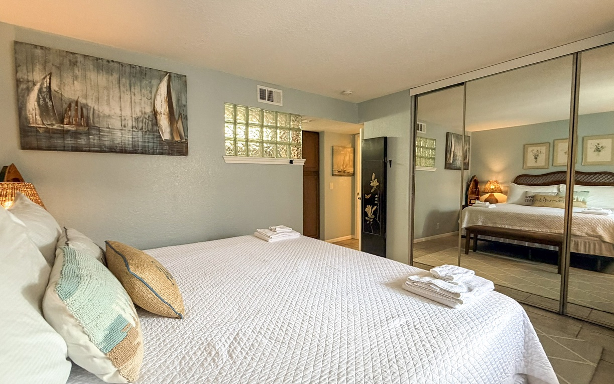 Your primary serene bedroom features a king bed, coastal artwork and mirrored closets that reflect natural light, creating an airy retreat for restful nights.