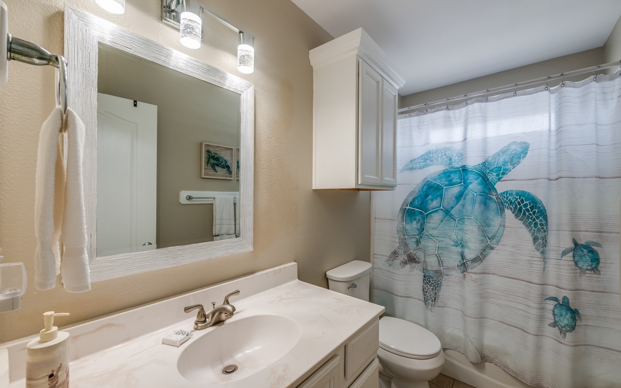 Refresh in your beautifully updated bathroom featuring coastal sea turtle artwork and crisp white finishes for a serene start to each day.