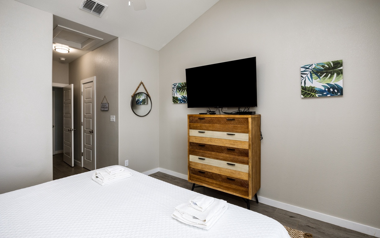 Unwind in your stylish bedroom featuring modern tropical decor, fresh linens, and entertainment at your fingertips.