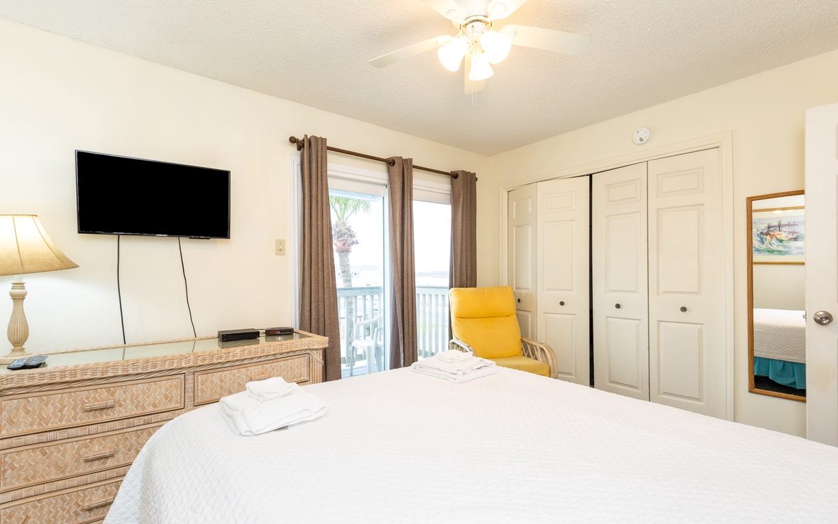 Relax in your comfortable bedroom with plush linens, TV entertainment, and bright natural light streaming through your private balcony access.