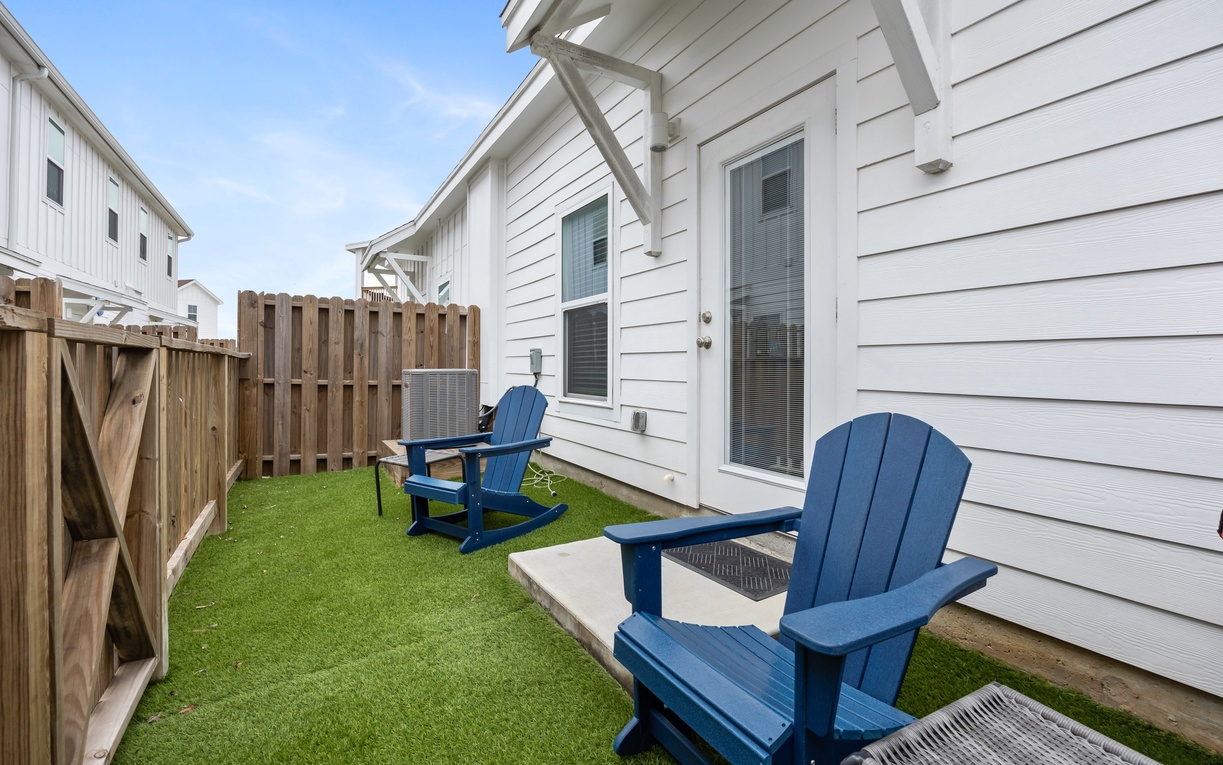 Relax in your private backyard oasis with bright blue Adirondack chairs perfect for morning coffee or evening conversations on lush green turf.