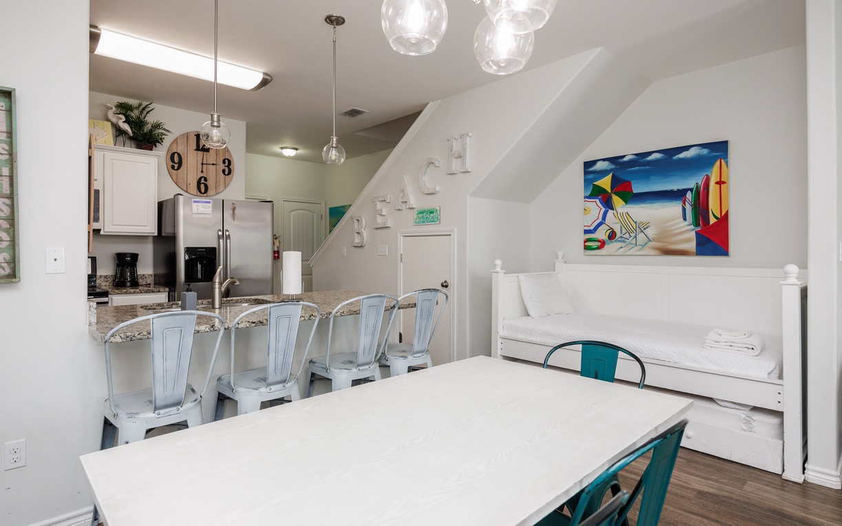 Your open-concept dining and kitchen space features coastal charm with globe pendant lights and cheerful artwork welcoming you home.
