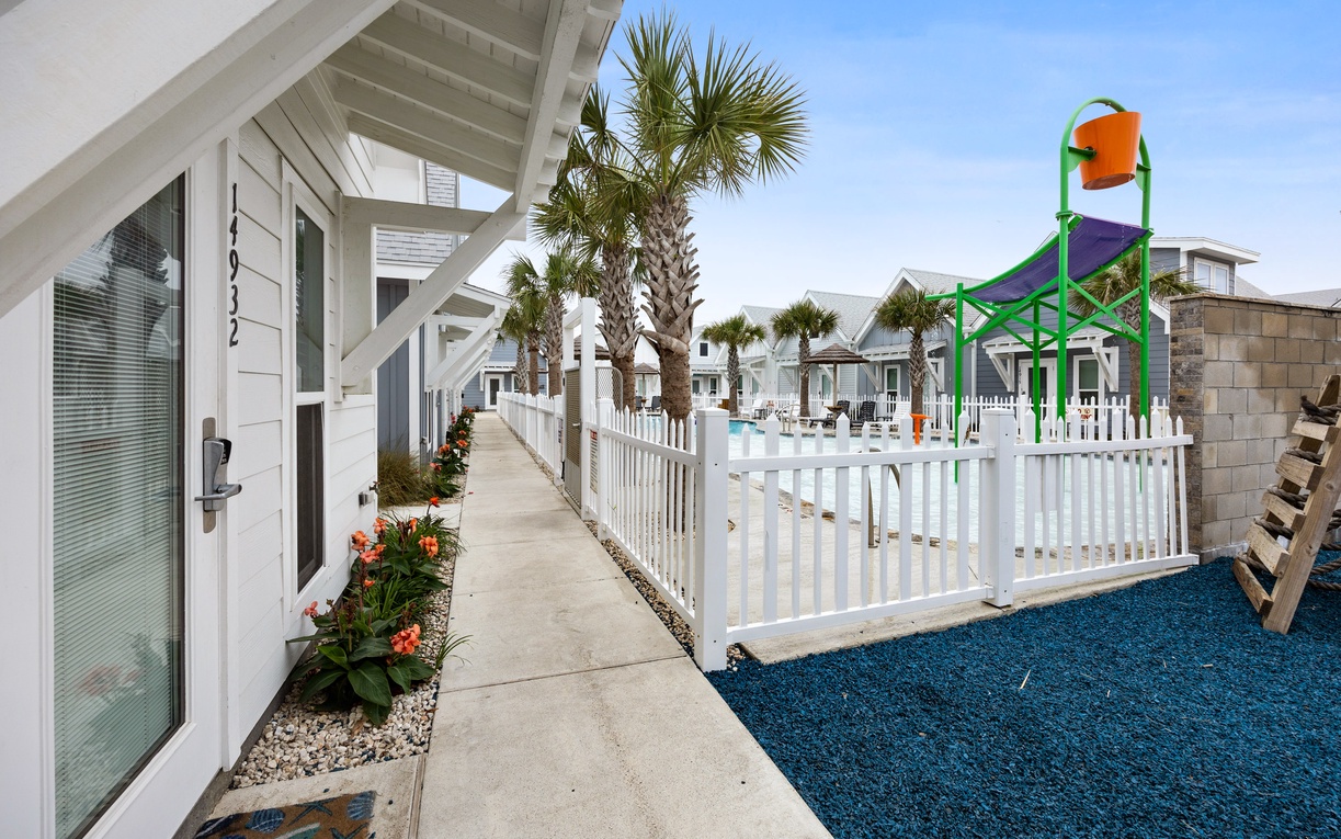 Coastal property featuring white buildings with tropical palm trees and a colorful children's playground in a family-friendly resort setting.