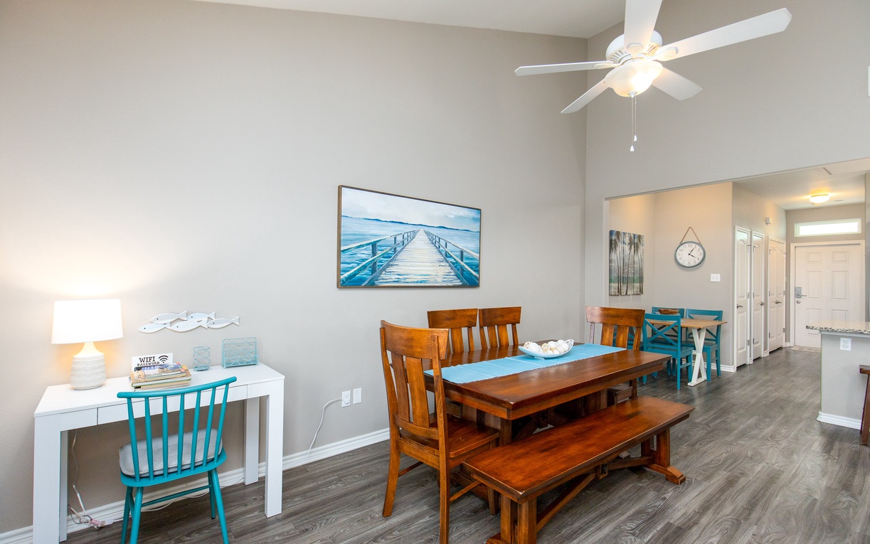 Your bright dining space features a beautiful wooden table and coastal artwork, creating the perfect spot for memorable meals together.