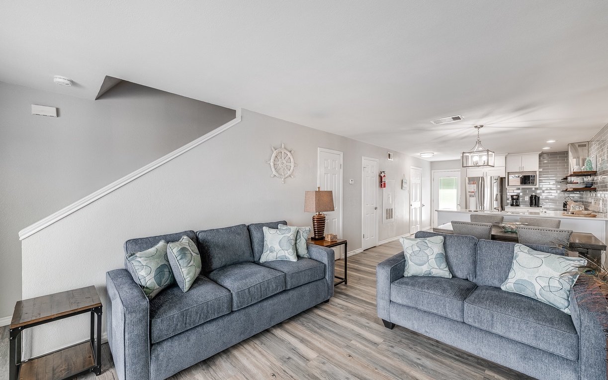 Sink into plush blue sofas where you'll unwind after your adventures, enjoying the open flow to your fully equipped kitchen.