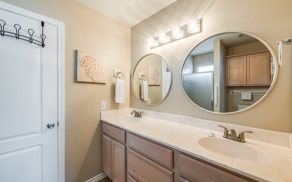 Step into your spacious bathroom featuring dual vanities, elegant round mirrors, and coastal-inspired décor for your morning routine.