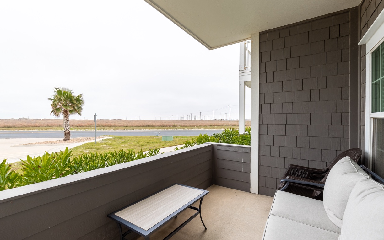 Unwind on your private covered balcony with comfortable seating and serene views of landscaped grounds and open space beyond.