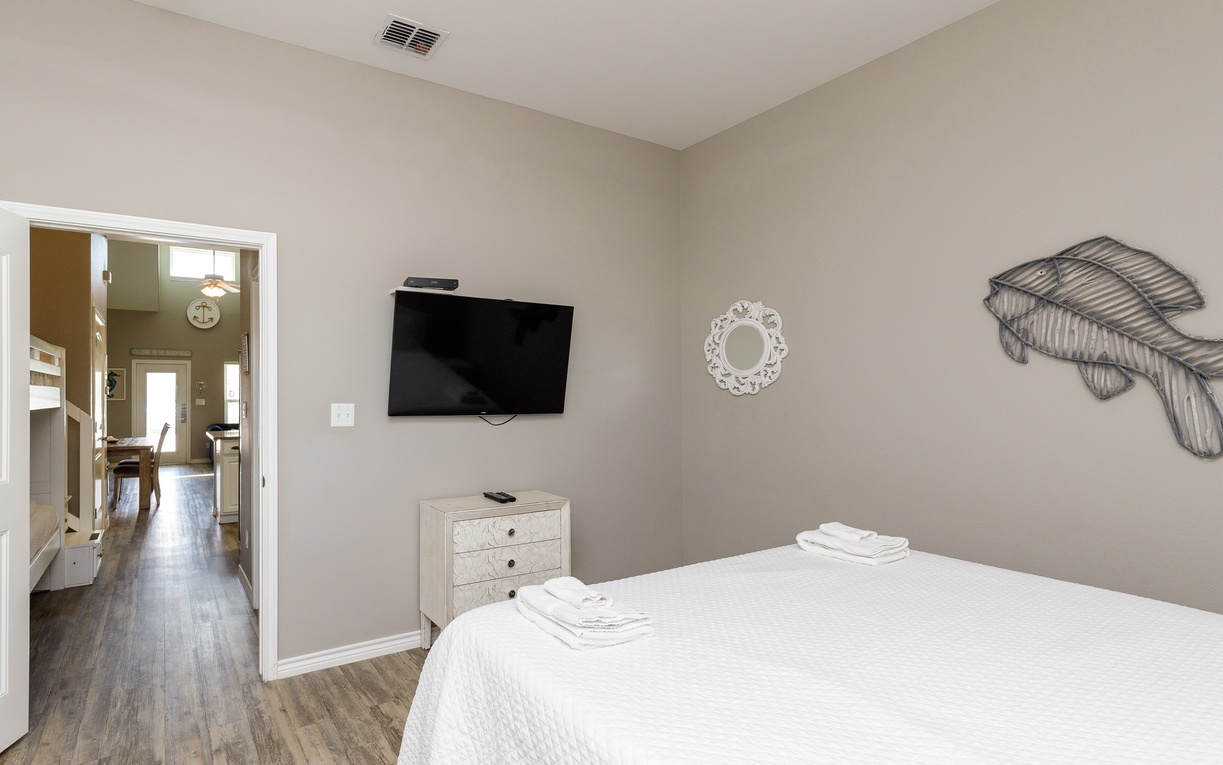 Sink into crisp white linens in your serene bedroom, where modern comfort meets thoughtful touches like your personal TV and coastal décor.
