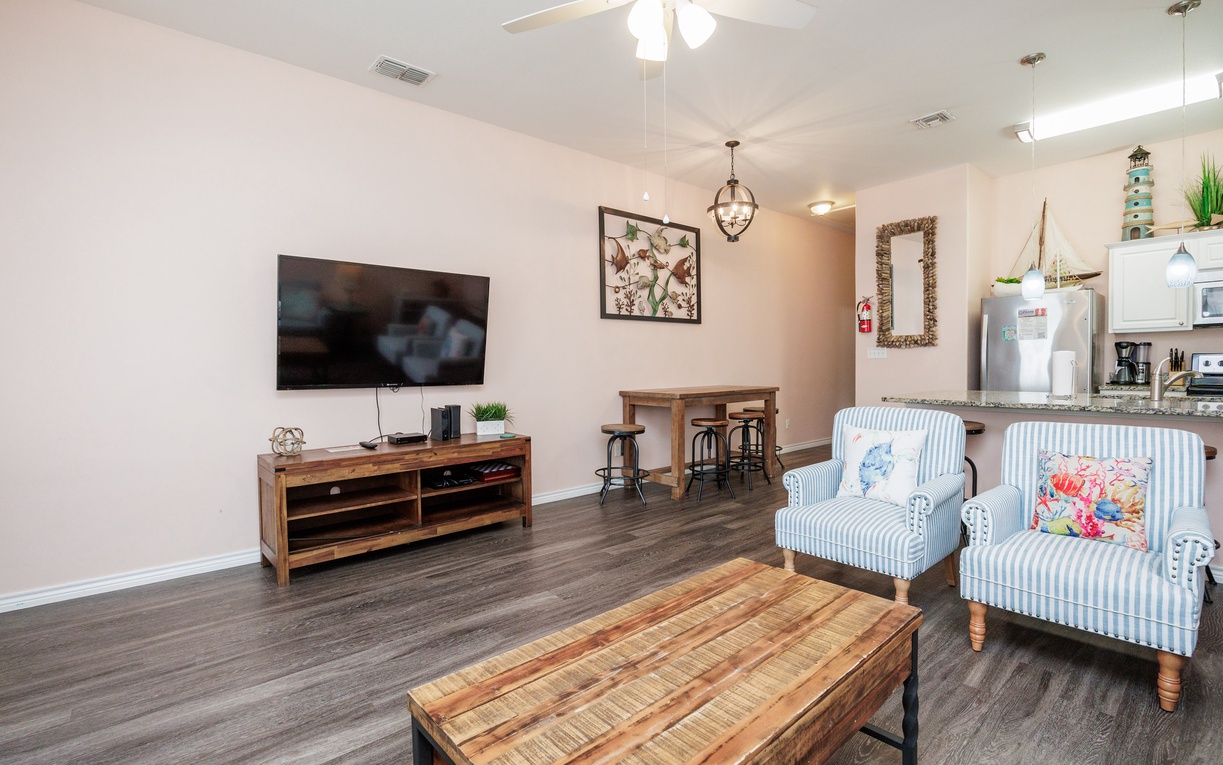 Unwind in your cozy living room featuring striped armchairs, rustic wood accents, and modern entertainment setup for perfect relaxation.