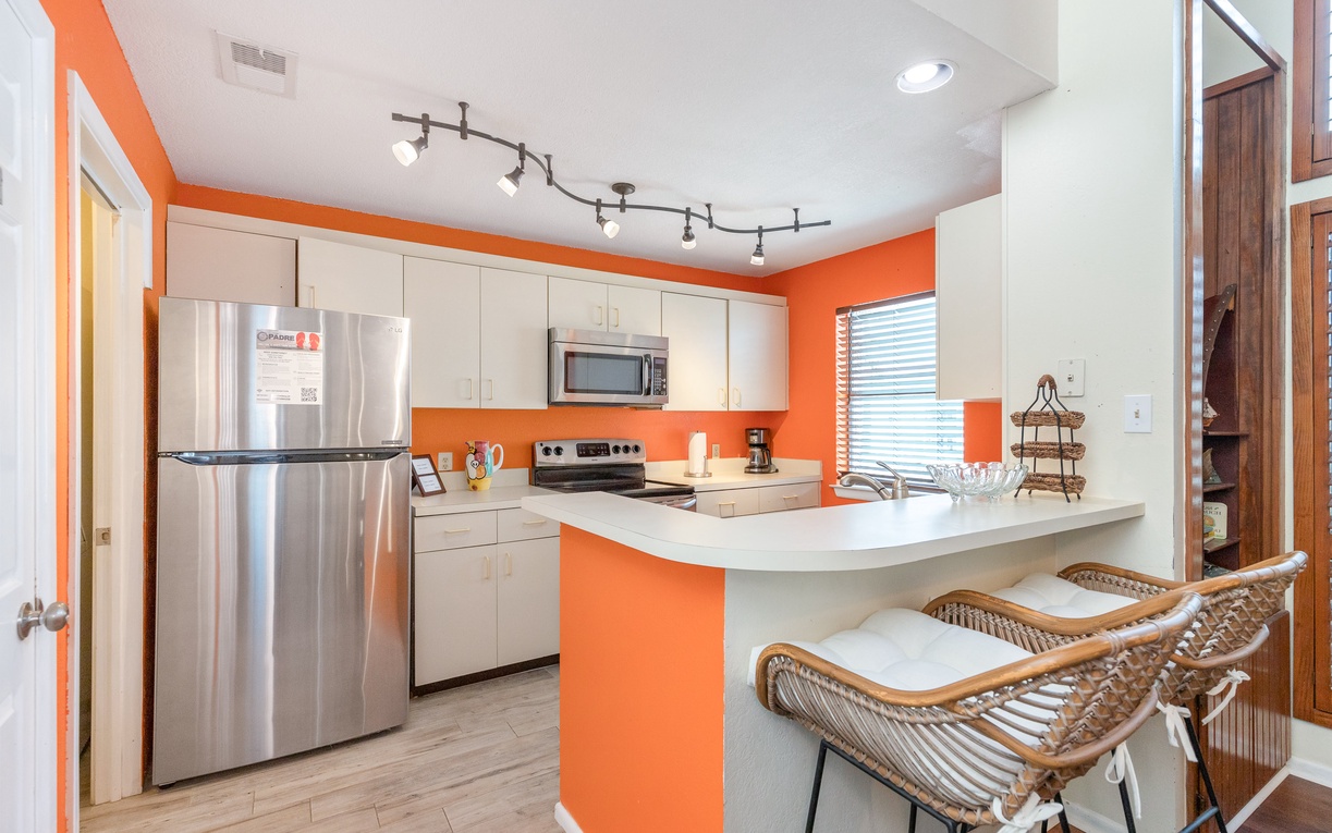 Your vibrant kitchen awaits with modern appliances and stylish orange accents, perfect for preparing meals together.