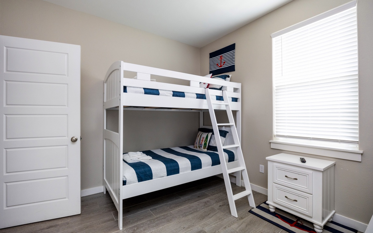 Your kids will love this cheerful bunk bed room with crisp white furniture and nautical blue accents creating the perfect space for adventure-filled dreams.