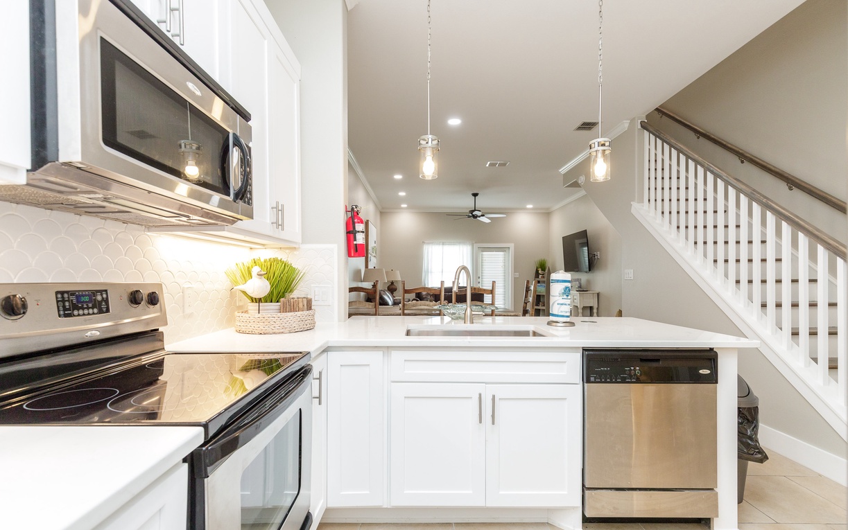 Your gleaming white kitchen features stainless steel appliances and pendant lighting, perfect for cooking memorable meals during your stay.