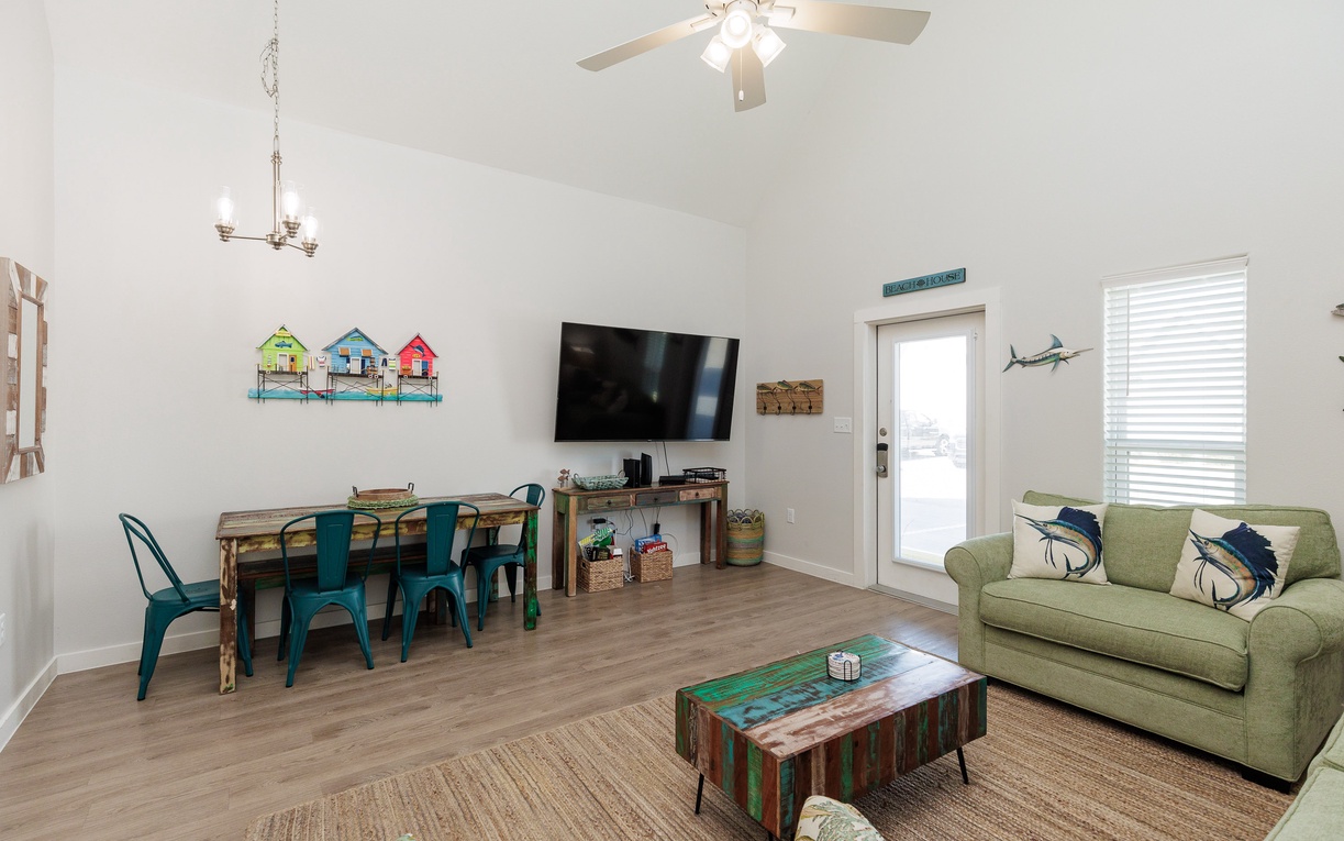 Relax in your bright coastal living room where green sofas invite lazy afternoons and the dining table awaits family meals.