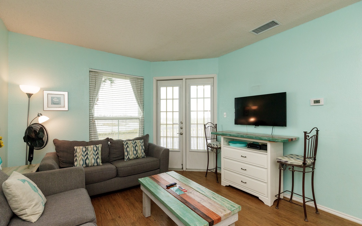 Sink into the cozy sectional sofa in your bright, beachy living room with soothing mint walls and modern entertainment setup.