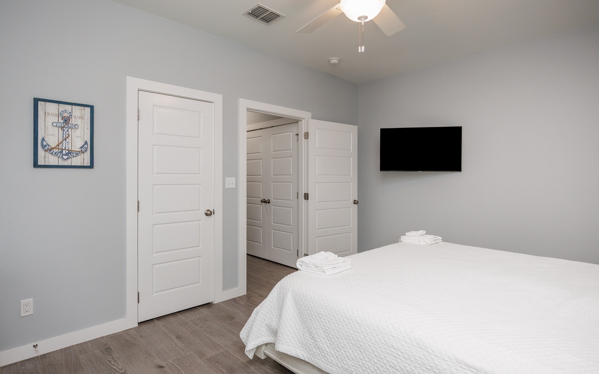 Drift into peaceful sleep on your plush bed while enjoying entertainment on the mounted TV in this serene, light-filled bedroom.