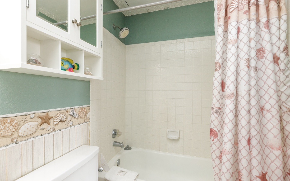 Unwind in your charming bathroom with coastal touches, white tiles, and convenient storage shelving for all your essentials.