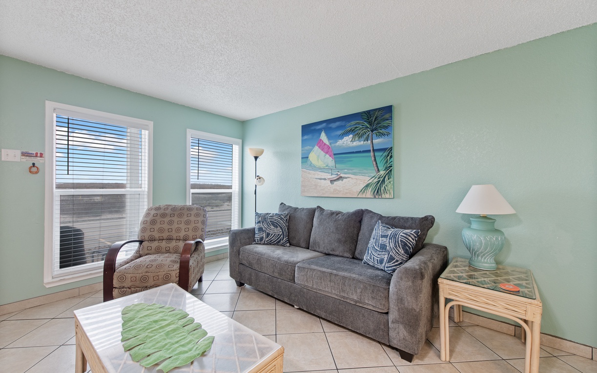 Unwind in your tranquil living room with coastal vibes, featuring comfy seating and tropical artwork.